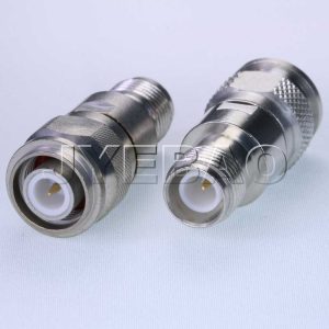 Two metal RF coax connectors with white insulators and gold center pins on a light surface.